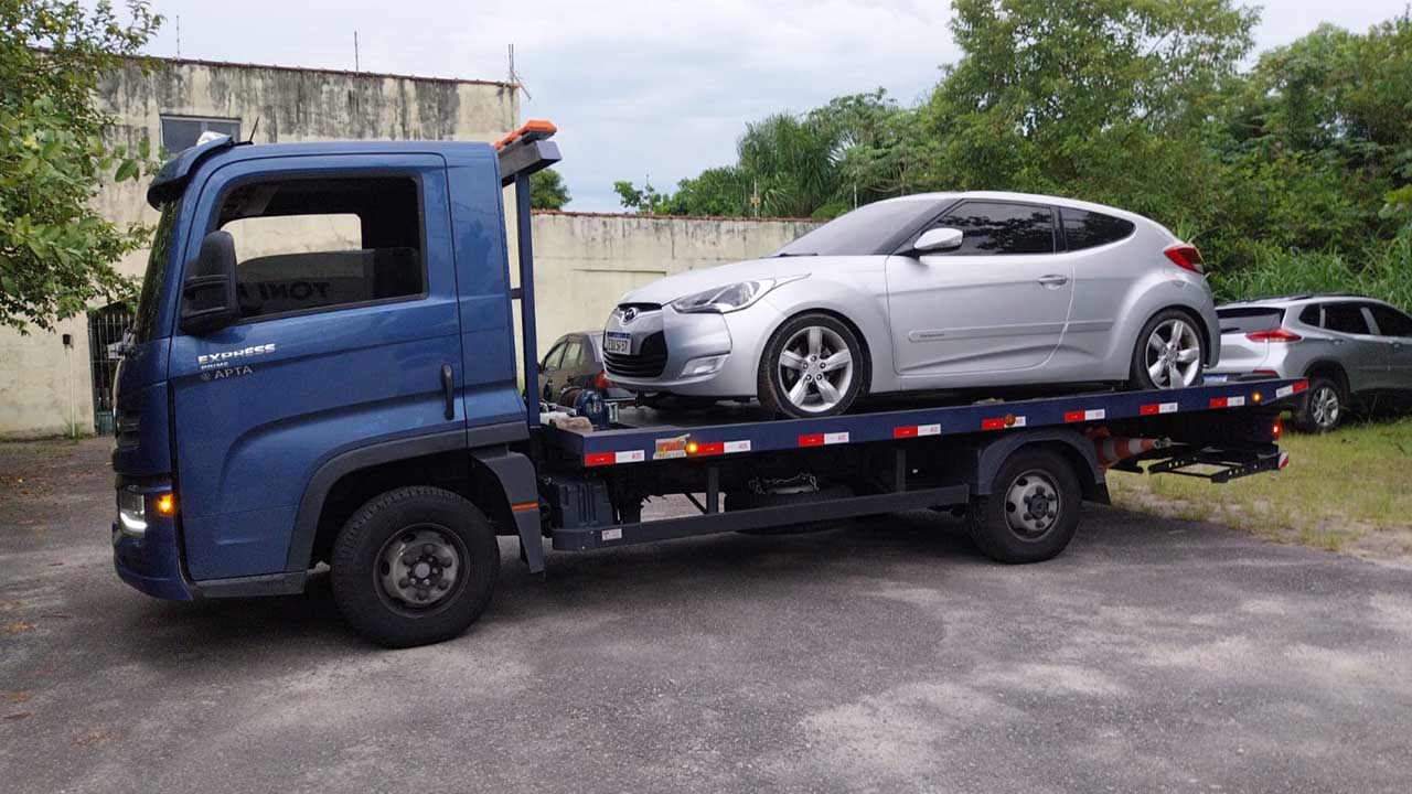 Guincho plataforma azul transportando um automóvel