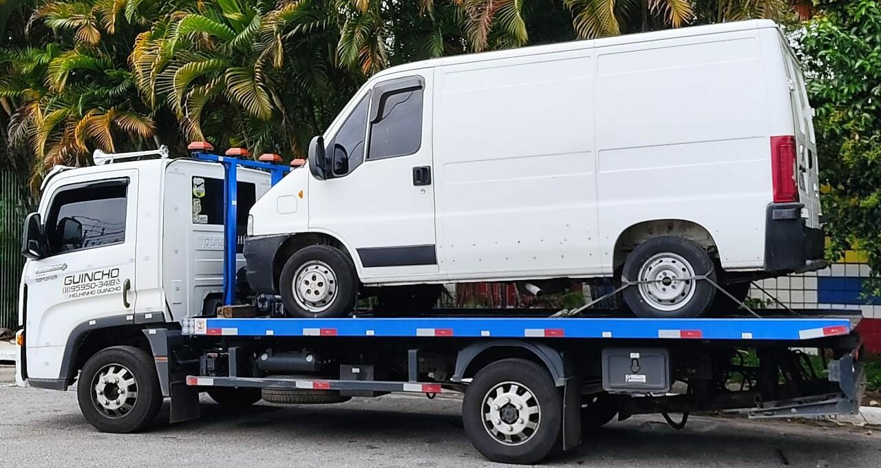 Guincho plataforma transportando um veículo utilitário